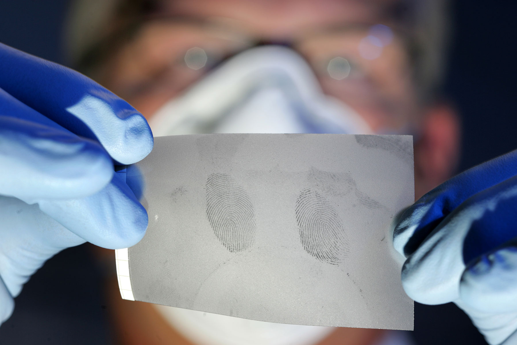 Kriminalbeamter hält eine Folie mit Fingerabdrücken
