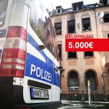 Polizeiwagen vor Brandobjekt mit Schriftzug: Belohnung 5000 Euro.