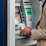 Ein Mann steht mit einer Bankkarte am Geldautomaten.