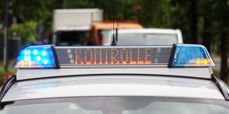 Streifenwagen mit Fokus auf Blaulicht. Anlange mit der Aufschrift "Verkehr".