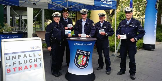 Fünf Polizeibeamte am Aktionsstand halten Postkarten in die Kamera.